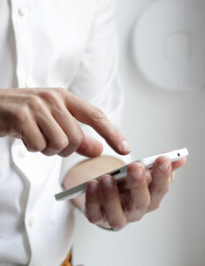 Person in white shirt pressing mobile phone screen